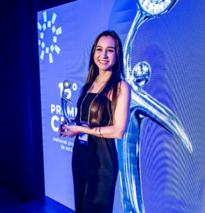 Foto da uma mulher branca segurando o troféu