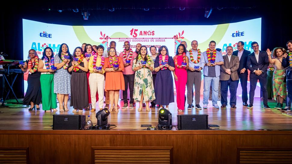Diversas pessoas vestidas em clima Aloha em cima do palco segurando o Prêmio