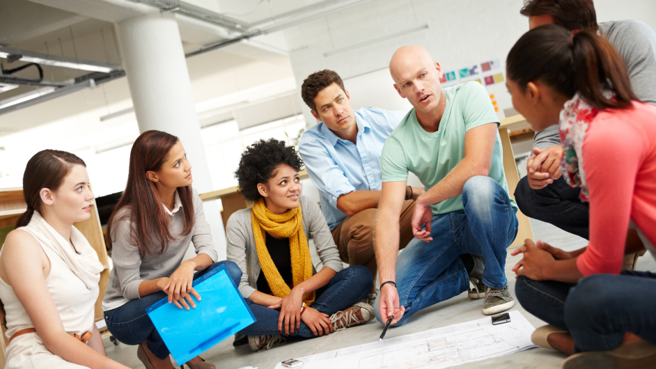 a imagem mostra várias pessoas participando de uma dinâmica de grupo, com cartaz na mão e expressão interessada