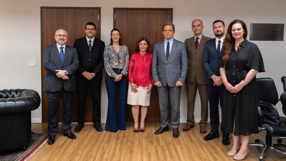 A imagem exibe representantes do CIEE, do TRT-2 e da UNIP reunidos durante a formalização da assinatura do acordo. Os participantes vestem trajes formais e estão posicionados em frente a portas de madeira, em uma sala com piso claro e mobiliário corporativo.