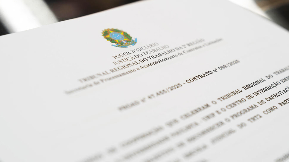 Close-up de um documento oficial com o brasão da República no topo, identificado como do Tribunal Regional do Trabalho da 2ª Região. A imagem está levemente desfocada nas bordas, com foco na área central do documento, reforçando o caráter formal da assinatura.
