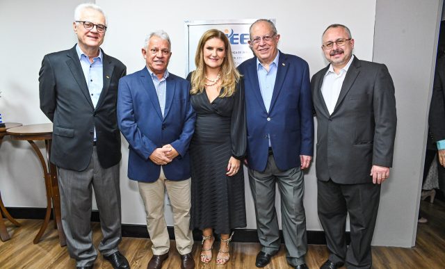 Treze pessoas posam sorrindo em frente a uma parede com palavras como "diversidade", "integração" e "CIEE".
